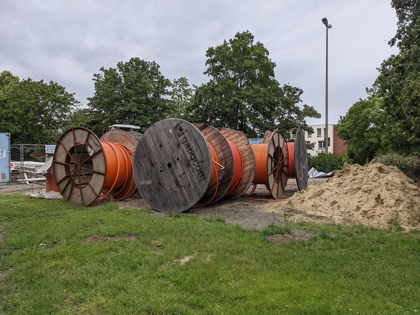 Large wooden drums of orange fiber conduit waiting at a construction site