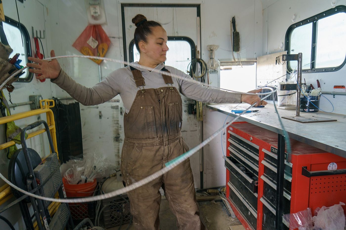 A technician uncoils fiber-optic cable inside a work trailer